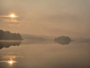 Mglisty wschód słońca nad jeziorem Bachotek
